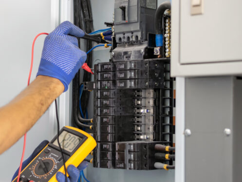An electrician testing an electrical panel