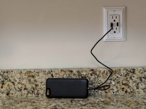 A cellphone charging phone case being charge on a wall outlet